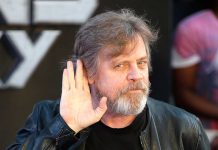 Mark Hamill tende la mano all'orecchio, con un sorrisone.