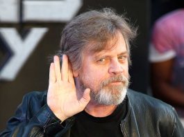 Mark Hamill tende la mano all'orecchio, con un sorrisone.