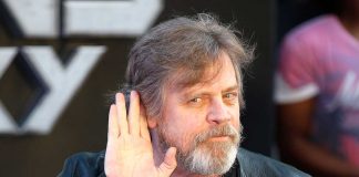 Mark Hamill tende la mano all'orecchio, con un sorrisone.